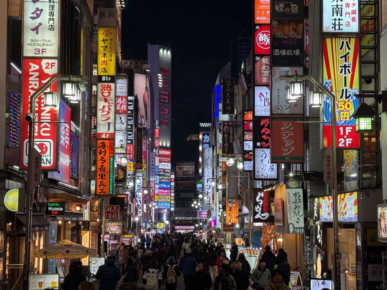 Une rue de Tokyo bondée la nuit, éclairée par les enseignes au néon des deux côtés
