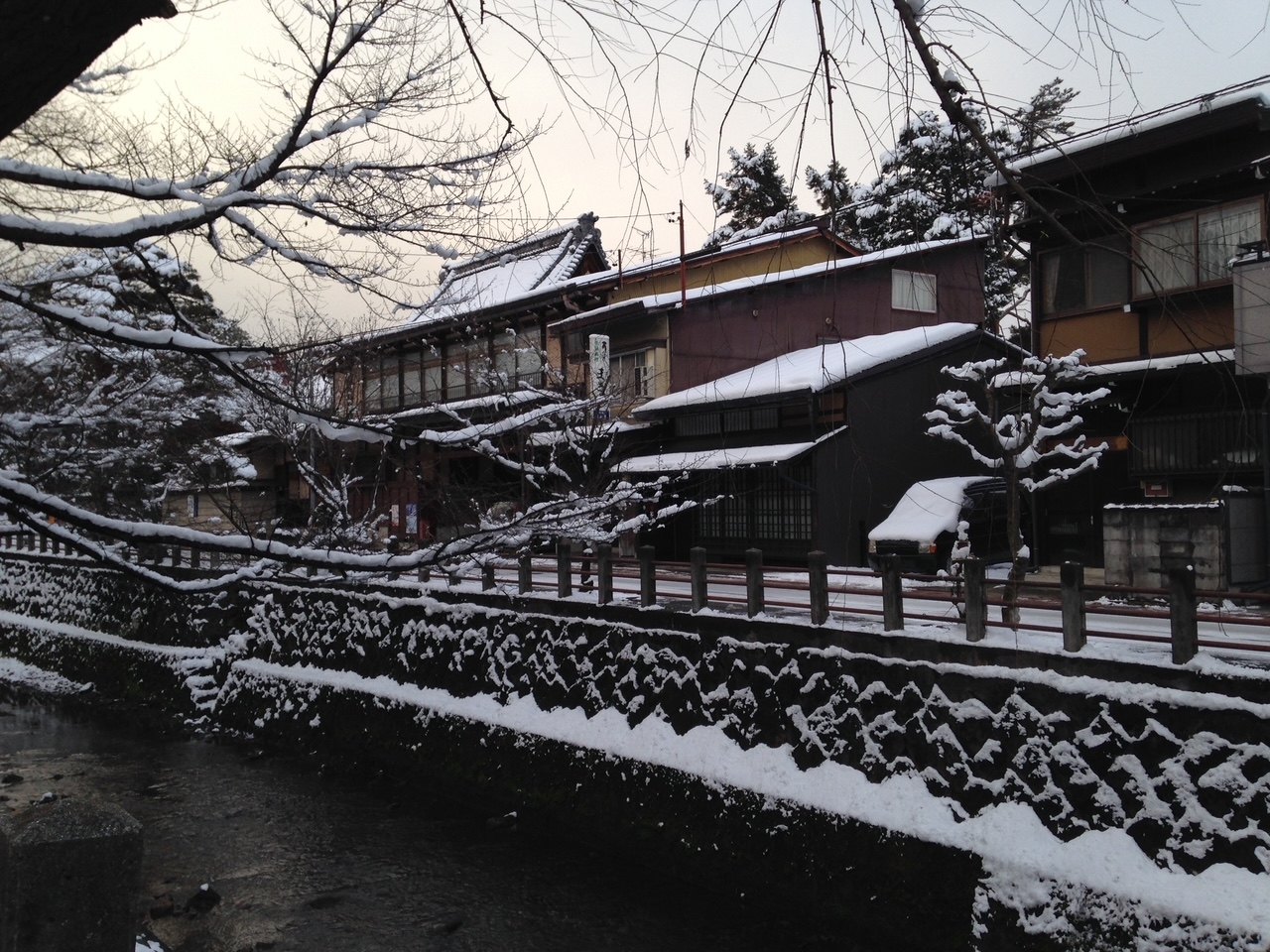 Maisons traditionnelles en bois le long d'un ruisseau bordé de neige